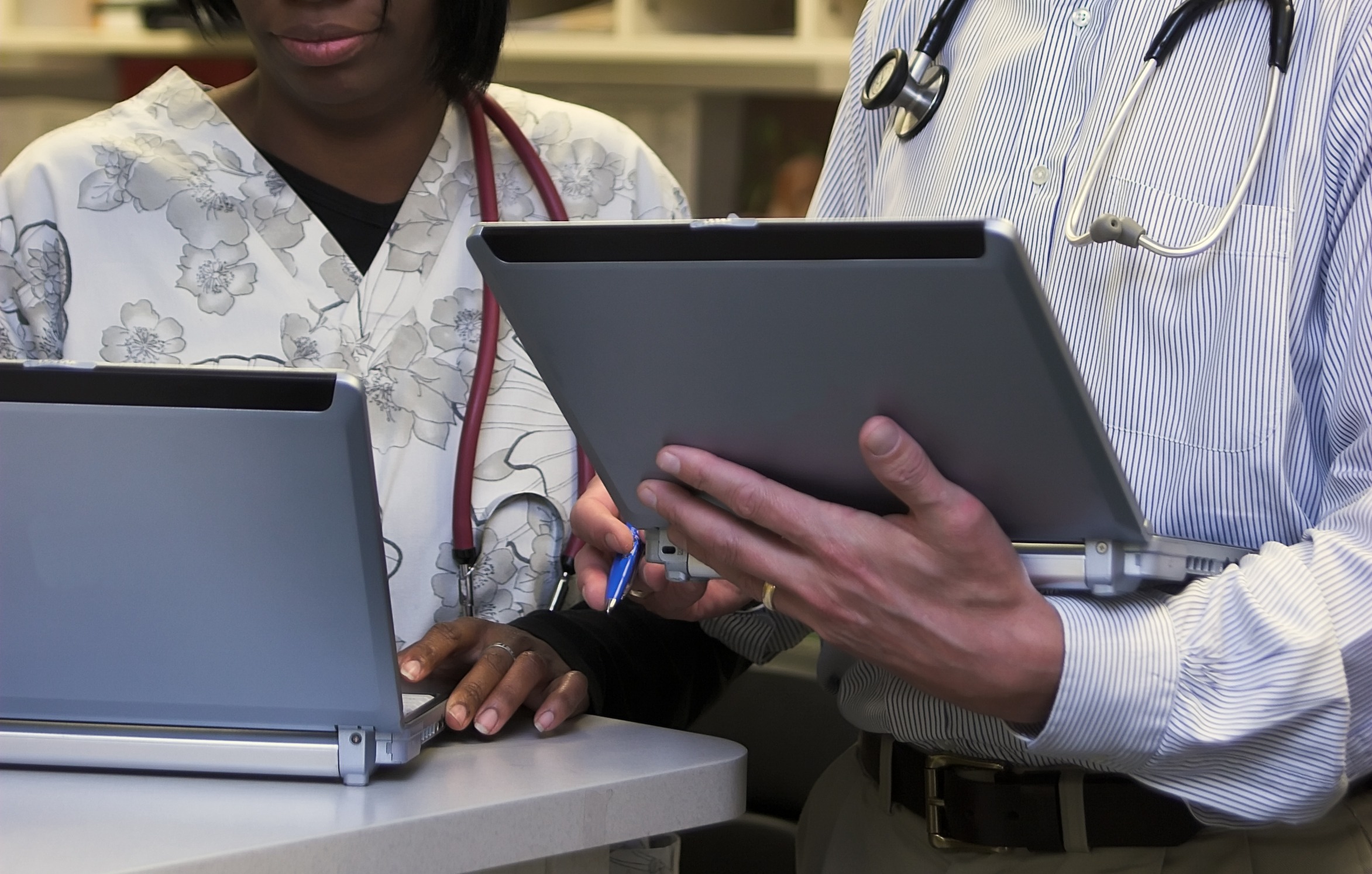 doctor and nurse discussing prognosis on laptop computers